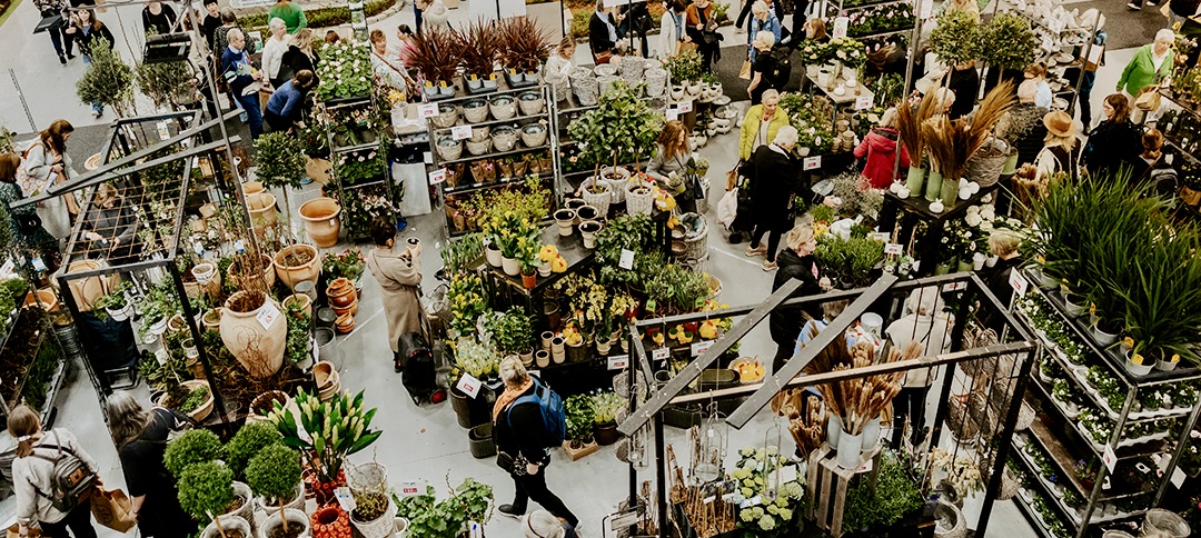 Bild över ett mässgolv fyllt med blommor och besökare